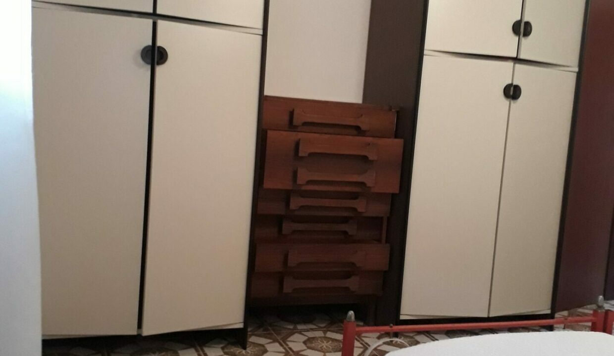 Camera attico Lido di Classe con armadi bianchi e cassettiera in legno
